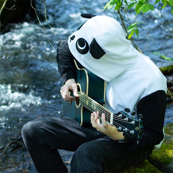 Me in a panda hoodie playing the guitar next to a river in the forest